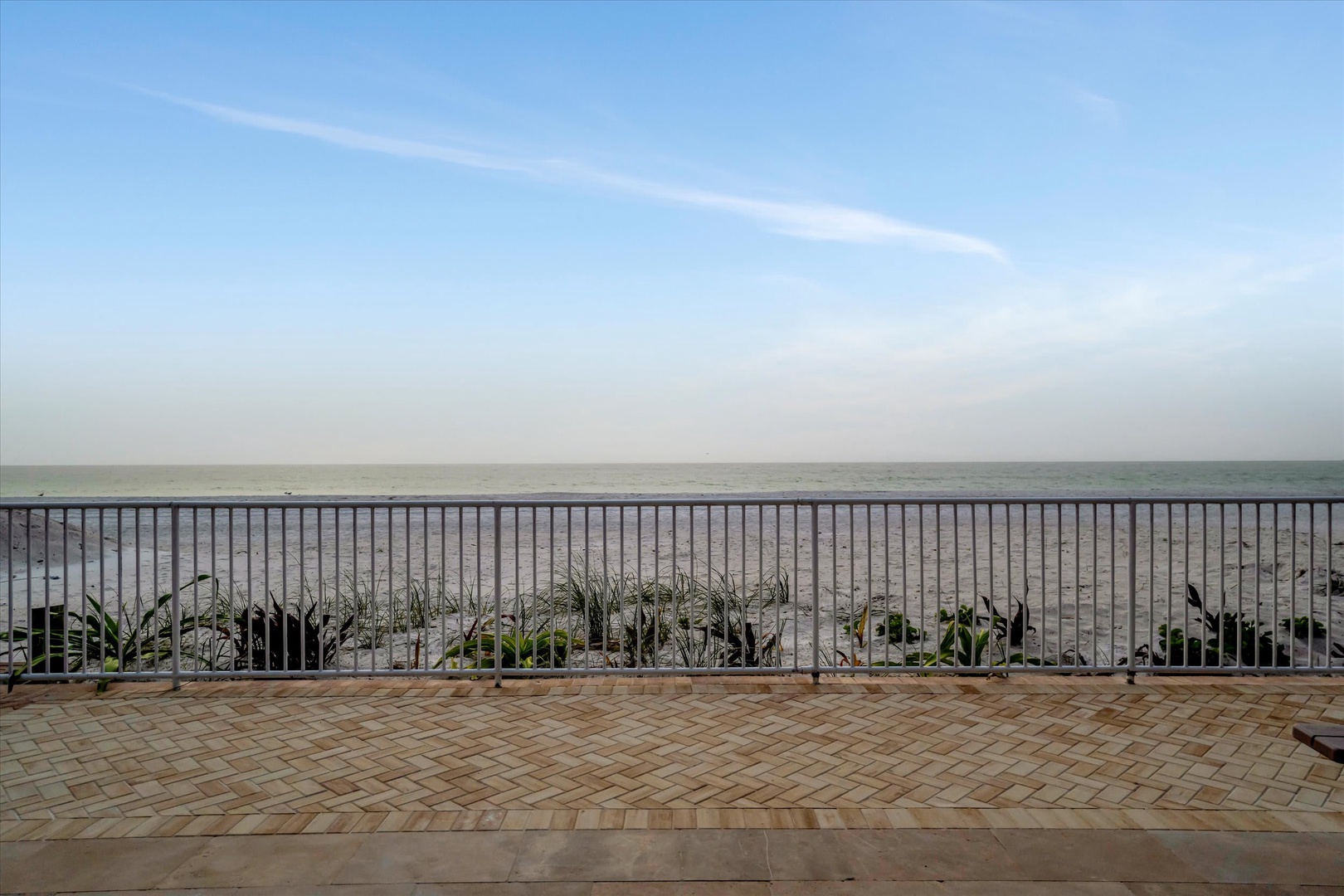A stunning beachfront location with direct access to soft sand and calm ocean waters stretching to the horizon.