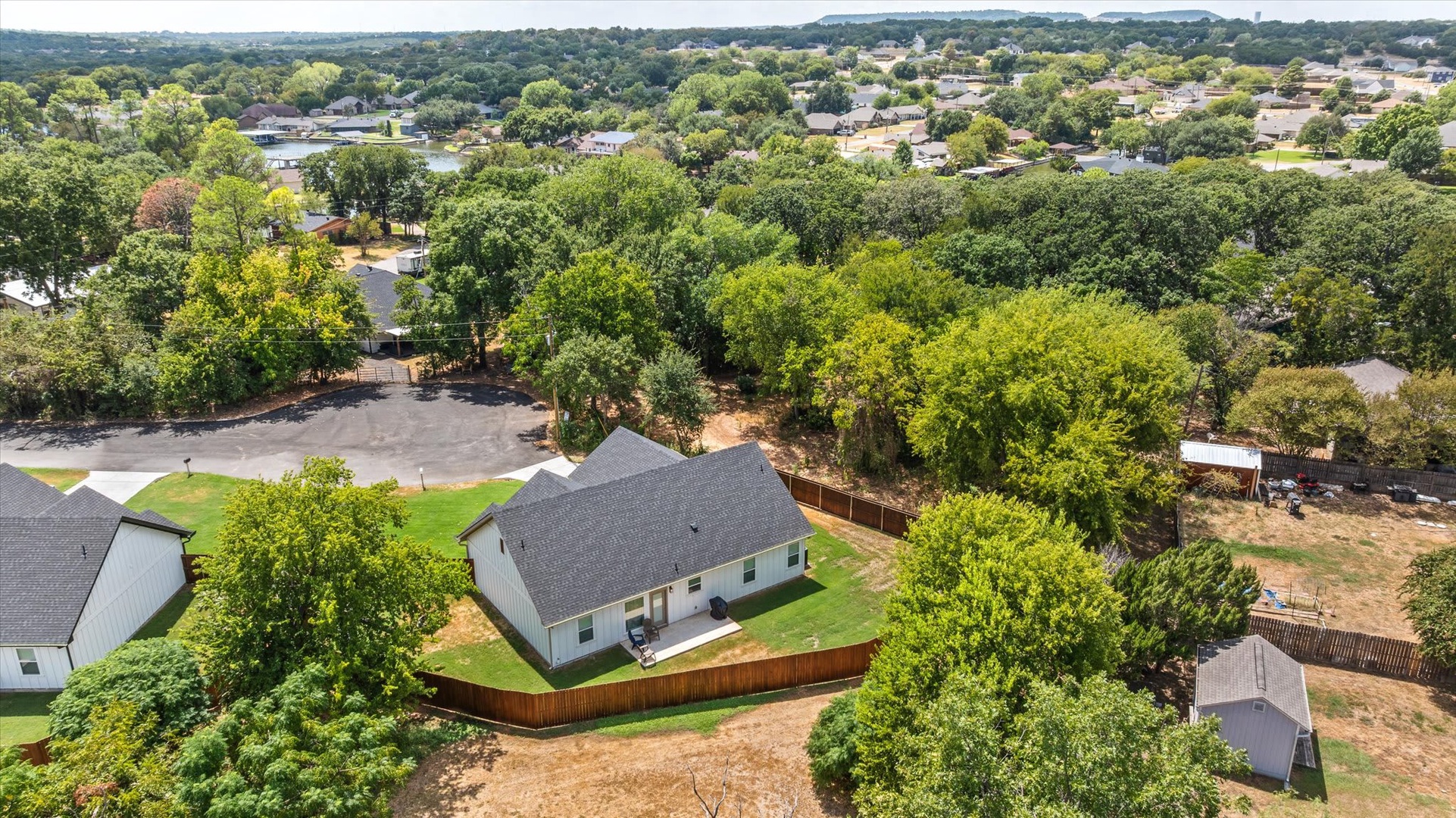 Aerial view of the vacation rental property, nestled in a tree-lined neighborhood with a spacious yard and outdoor patio area.