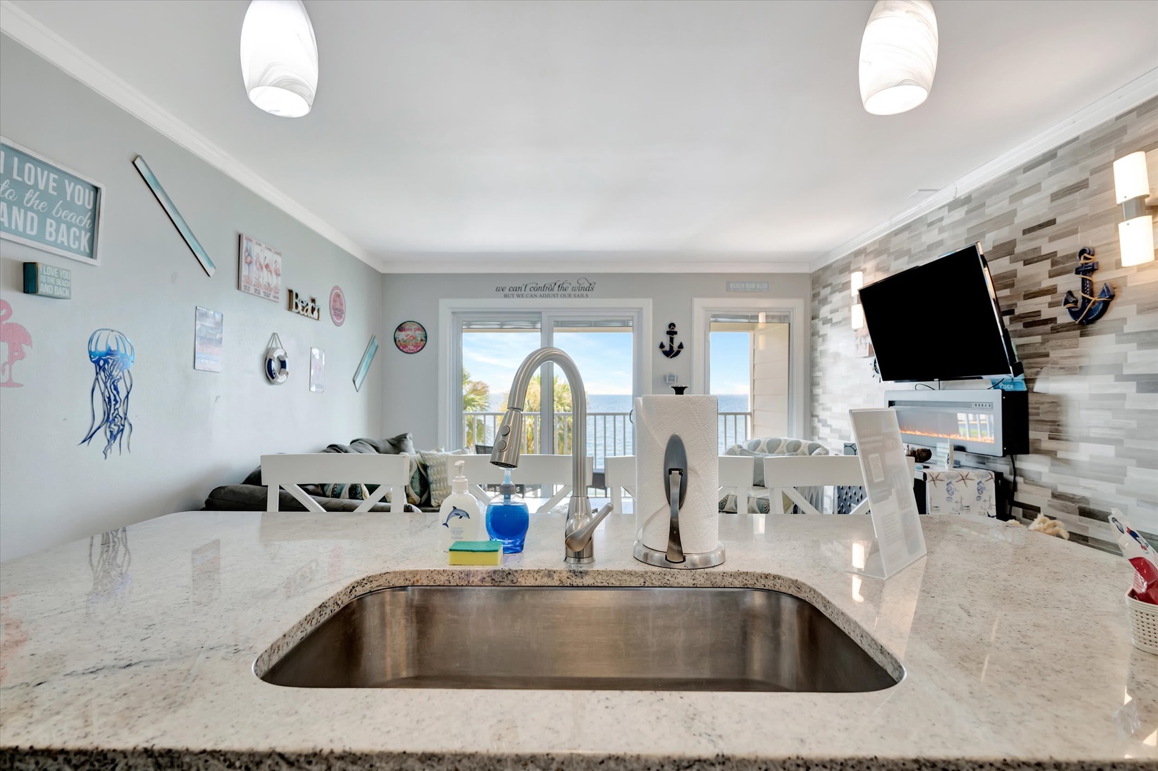 You'll love this open kitchen with gleaming granite counters and ocean views through the glass doors—perfect for morning coffee as the sea breeze drifts in.