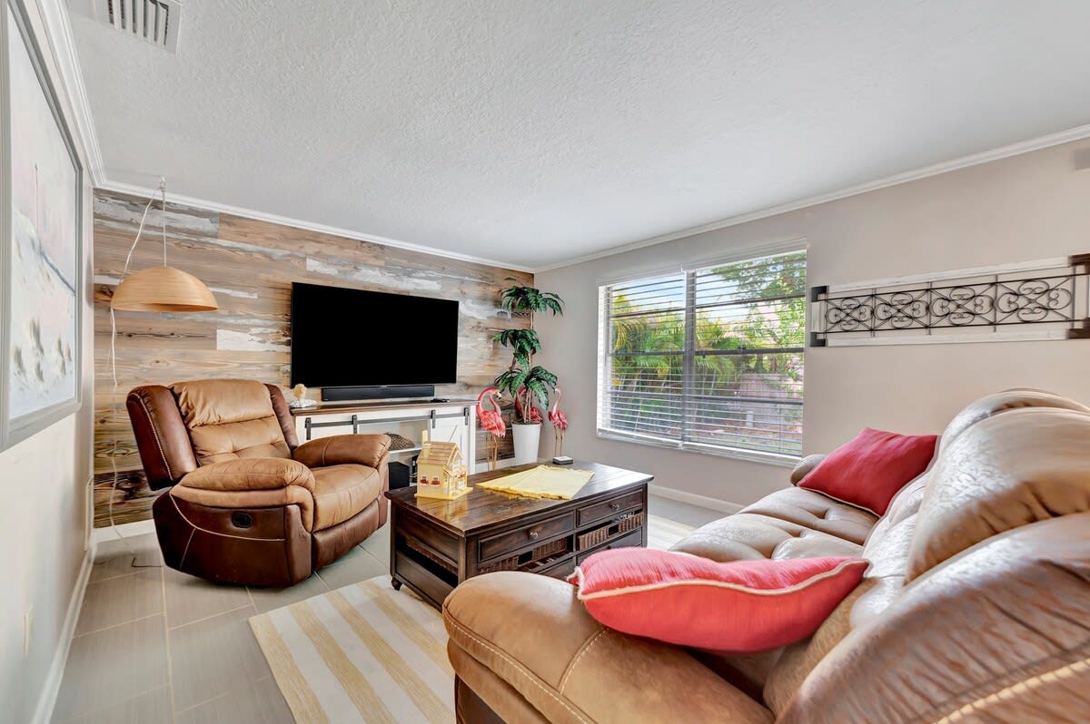 Unwind in your cozy living room with plush seating, warm wood accents, and natural light streaming through large windows—perfect for relaxing after a day of exploring.