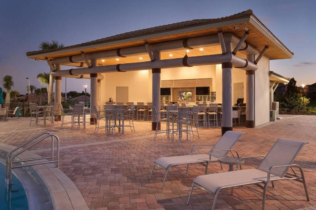 An inviting outdoor poolside area with a covered bar, comfortable loungers, and high-top seating awaits your relaxation and entertainment.