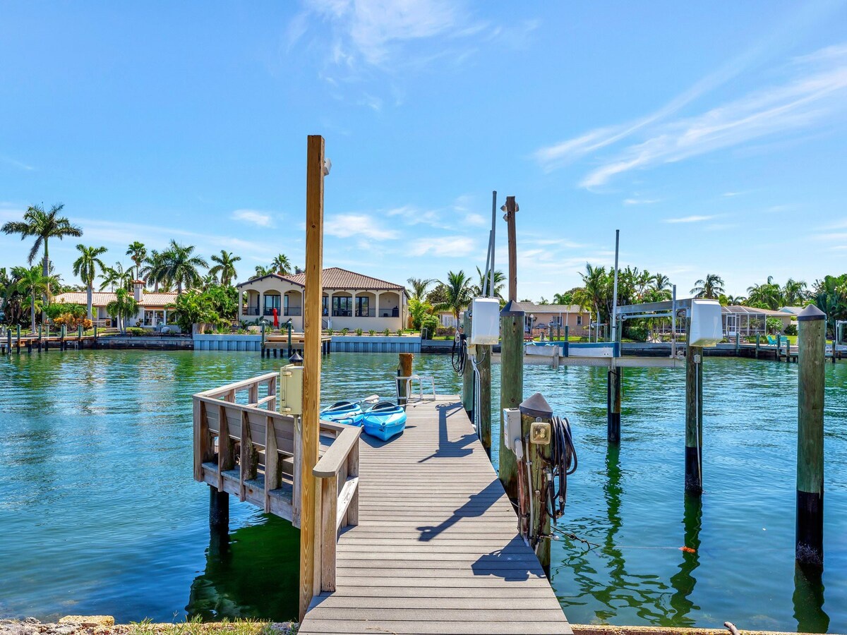 This waterfront property offers a private dock with direct access to calm, sparkling waters. Palm trees and coastal homes line the tranquil canal, perfect for boating and peaceful mornings by the water.