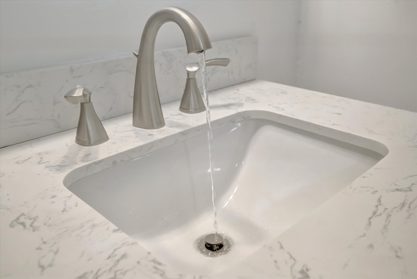 Refresh in a pristine bathroom featuring a marble countertop, sleek brushed nickel fixtures, and a deep undermount sink—your peaceful retreat for morning rituals.