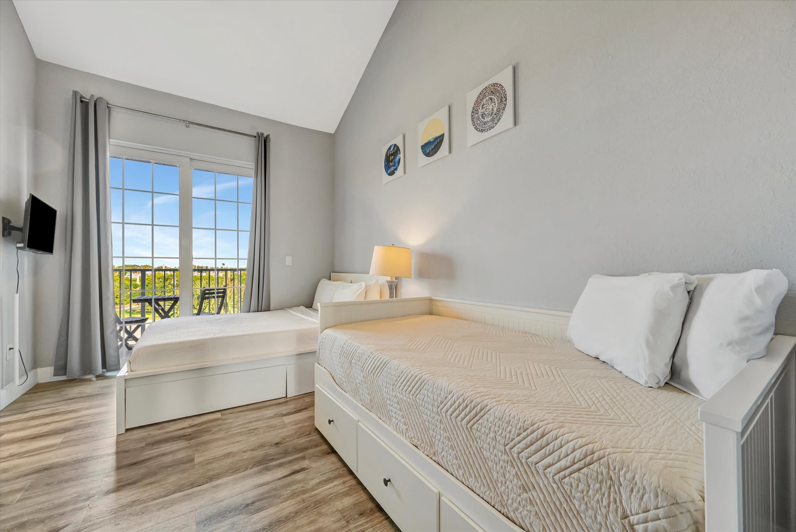 Settle into this bright, serene bedroom where vaulted ceilings and soft natural light create your peaceful retreat. Two cozy beds, tasteful coastal décor, and a private balcony invite you to unwind completely.