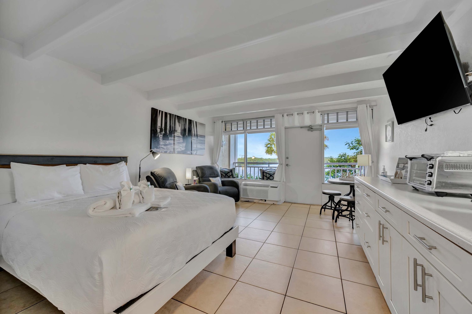 Step into your bright, airy retreat with crisp white linens and waterfront views through French doors opening to your private balcony. Your kitchenette keeps essentials close while you unwind.