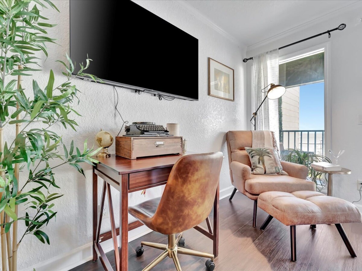 Settle into your cozy corner with a vintage typewriter, plush reading chair, and lush greenery—your perfect spot to unwind with a good book or catch up on work with inspiring views beyond.