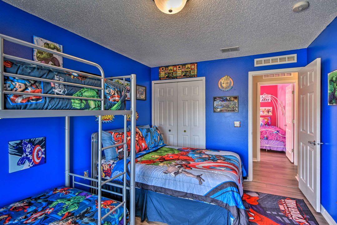 This colorful themed bedroom features a bunk bed and twin bed, perfect for kids who dream of adventure. The bright blue walls and playful décor create a fun, welcoming space.