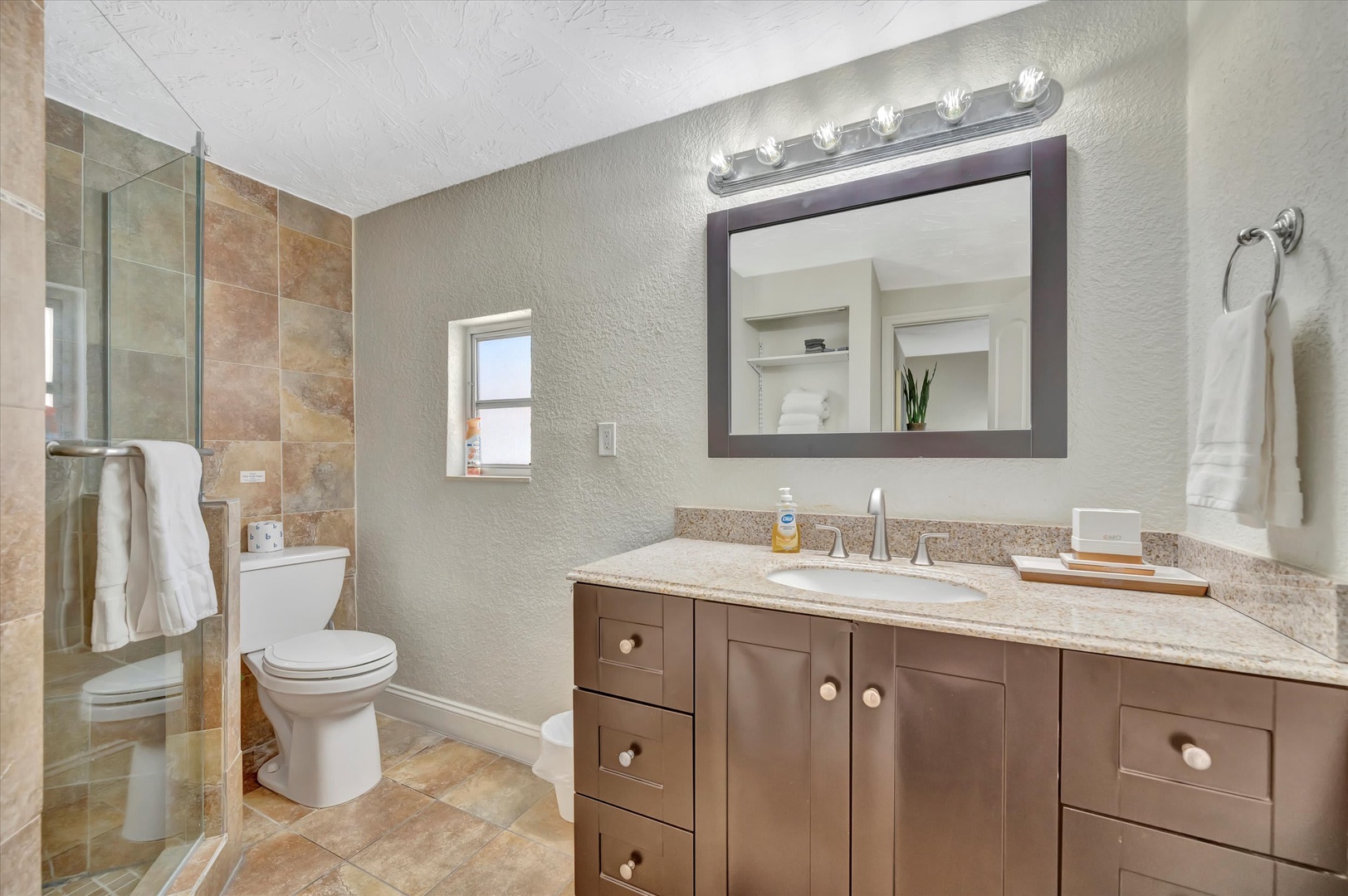 Freshen up in your beautifully appointed bathroom, featuring warm tones, a spacious vanity, and a walk-in shower with elegant tile work that invites you to unwind.
