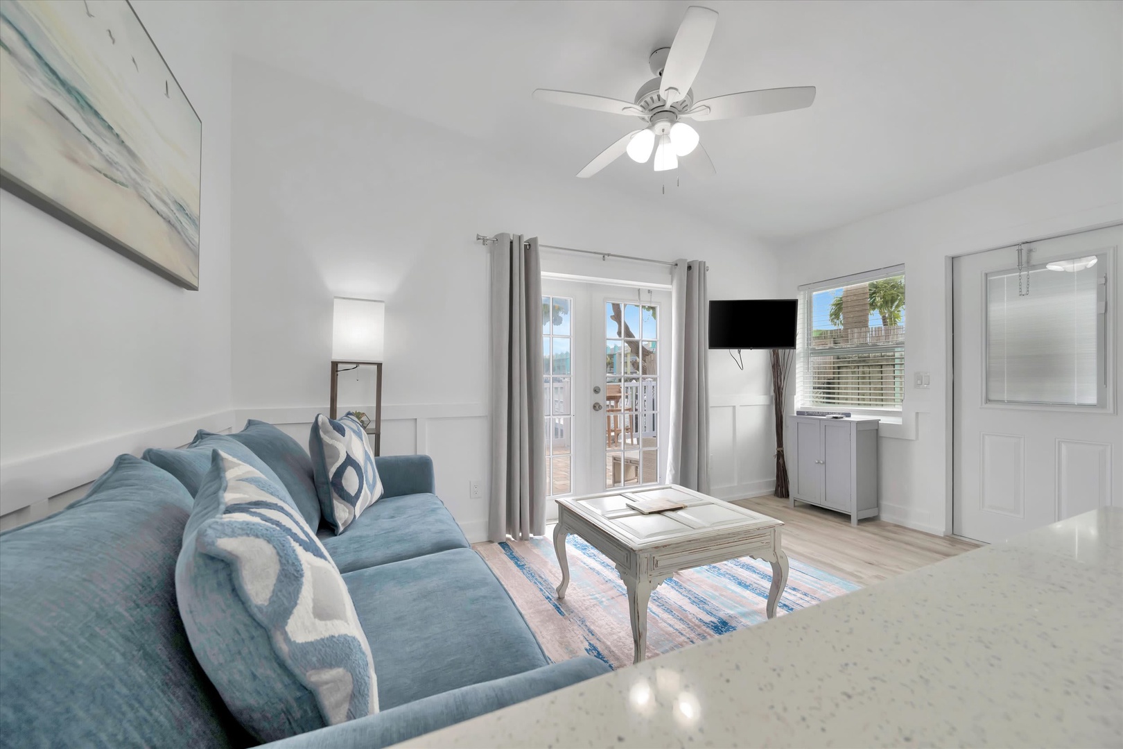 Step into your bright coastal escape, where a plush turquoise sofa invites you to sink in and unwind. Sunlight streams through glass doors opening to your private outdoor space, while soothing ocean-inspired decor sets the perfect beach retreat vibe.