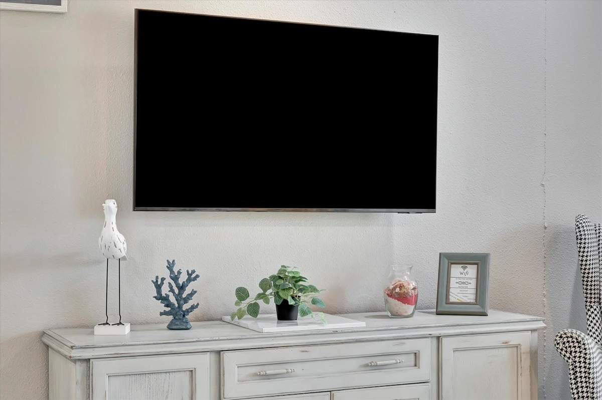 Unwind in your space with a sleek TV perfectly positioned above coastal-inspired décor—your personal retreat awaits after a day of exploration.