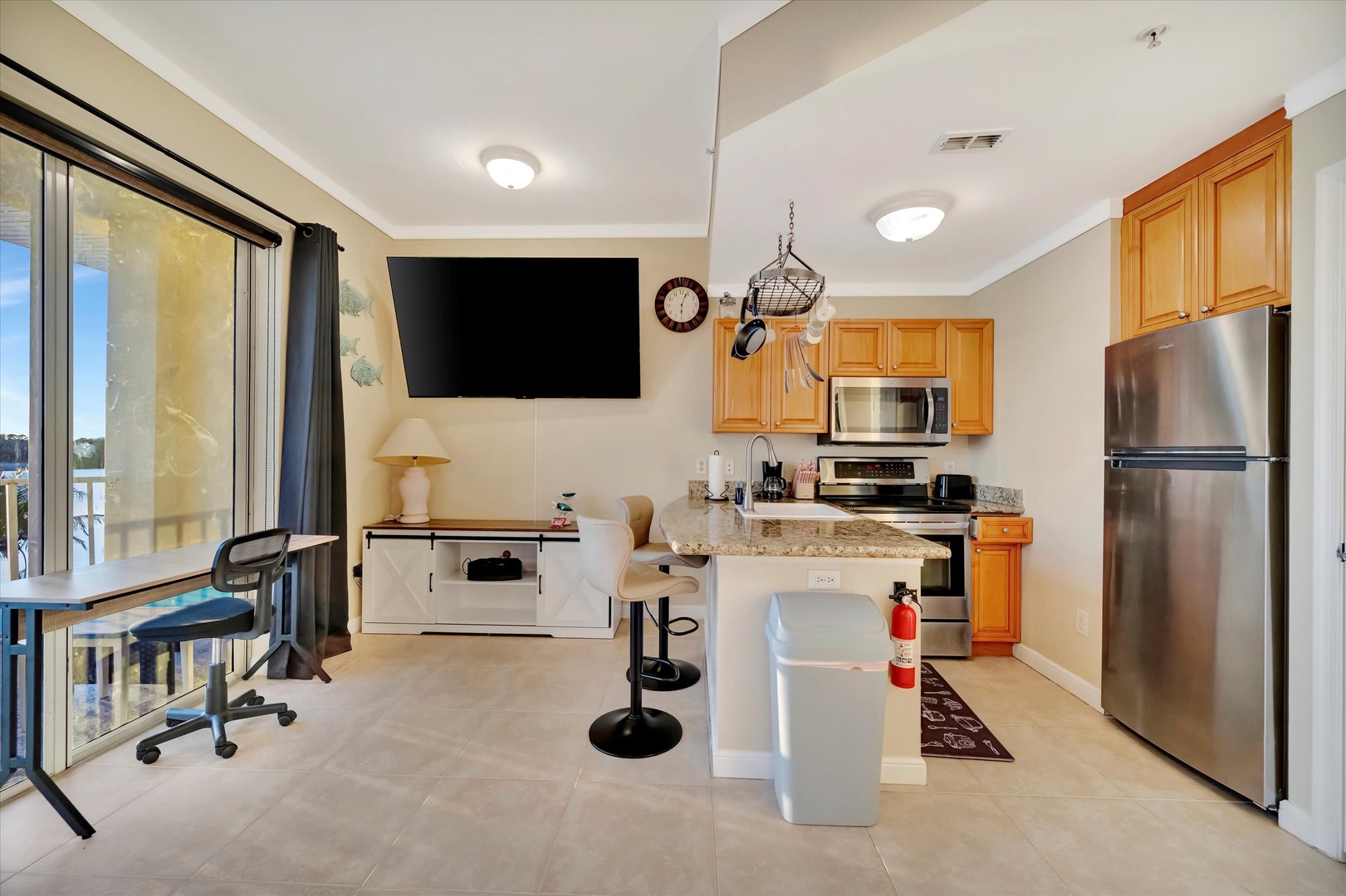 Step into your bright, open-concept space with a fully equipped kitchen, modern stainless appliances, and a breakfast bar perfect for morning coffee. Work from the desk by the sliding doors, or simply relax in your inviting living area.