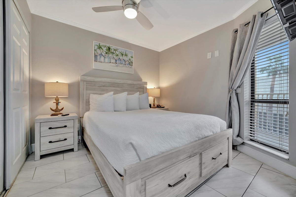 Drift off under the gentle breeze of your ceiling fan, wrapped in crisp linens and soft coastal light. Your peaceful retreat awaits, styled with coastal charm and everything you need for a restful night.