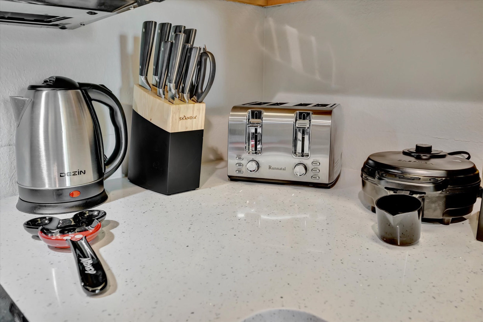 Your fully-equipped kitchen corner features everything you need for easy mornings—electric kettle, toaster, waffle maker, and a complete knife set ready for meal prep.