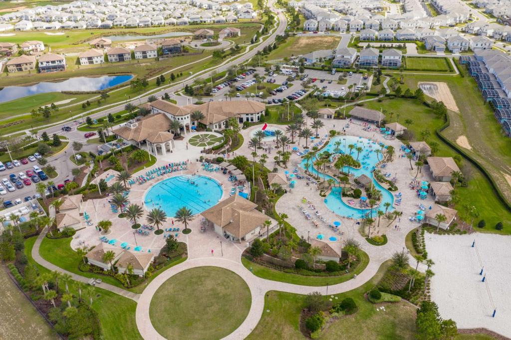 Aerial view of the resort community showcasing an expansive aqua park with winding lazy rivers, multiple swimming pools, tropical palm trees, tiki-style cabanas, and surrounding residential neighborhoods.