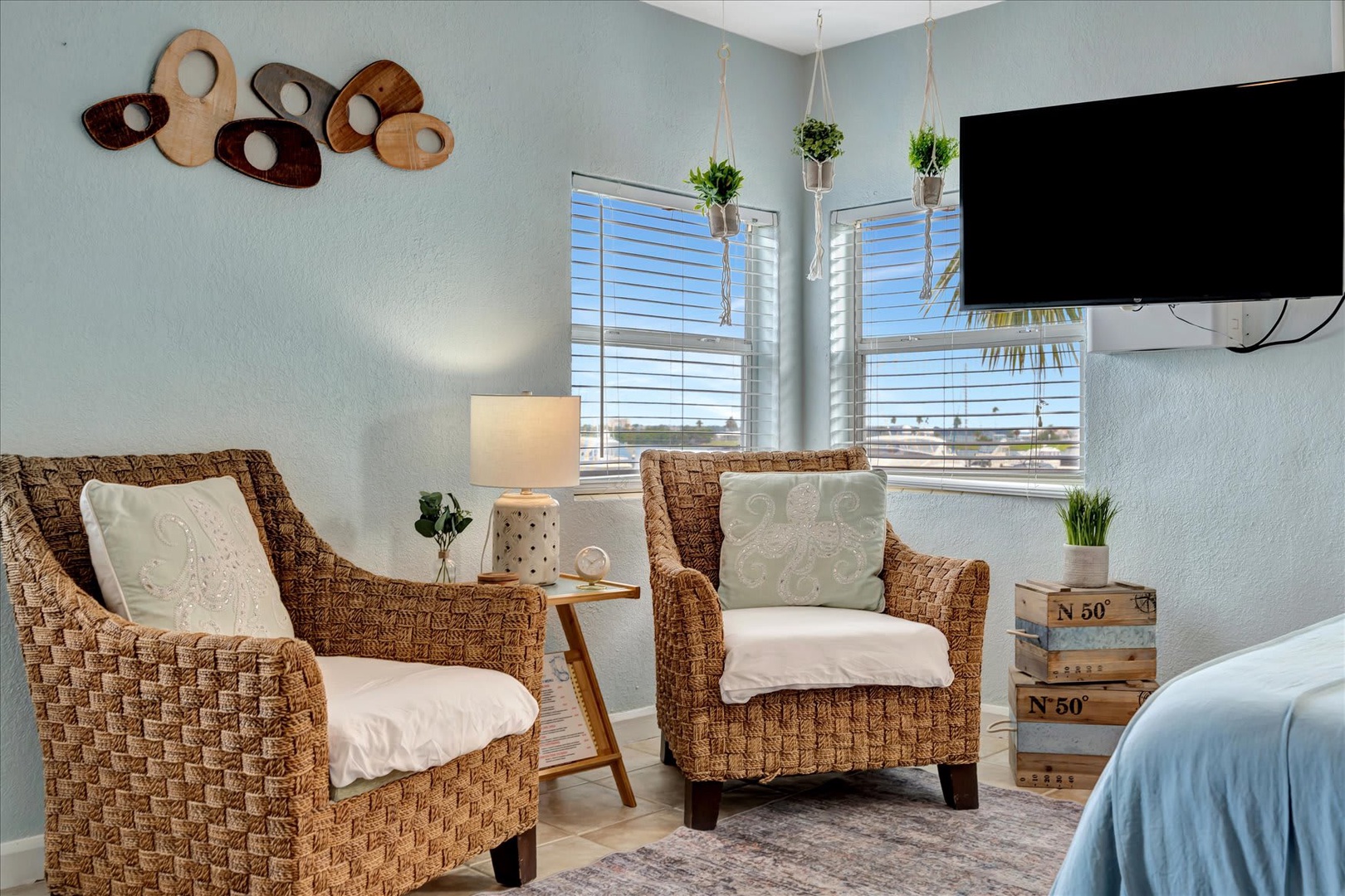 Curl up in your cozy corner seating area with natural light streaming through plantation shutters. This peaceful nook offers the perfect spot to unwind with coastal charm and comfortable woven chairs.