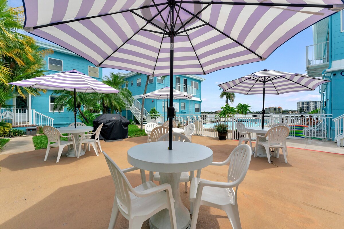 Gather under cheerful striped umbrellas and soak up the coastal atmosphere. Your outdoor seating overlooks a sparkling pool and tropical palms, perfect for morning coffee or evening cocktails with a waterfront backdrop.