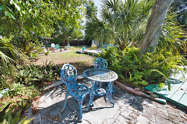Settle into your private garden retreat with tropical palms and lush greenery. Your morning coffee spot awaits under the shade, with colorful seating perfect for soaking in the peaceful outdoor atmosphere.