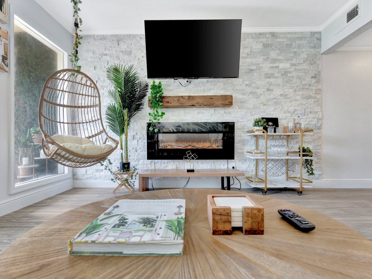 Settle into your stylish living space where modern design meets cozy comfort. The whitewashed brick wall, electric fireplace, and hanging chair create a relaxing retreat perfect for unwinding after exploring the area.