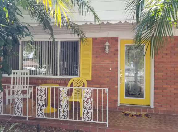 Nestled under swaying palms, this cheerful entrance welcomes you to your tropical retreat. The covered patio offers a shaded spot to unwind after a day of adventure, while vibrant yellow shutters add a pop of island charm.