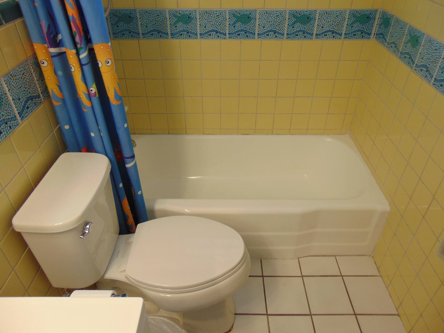Your private bathroom features a full tub and shower combo, with cheerful ocean-themed accents and sunny yellow tile to brighten your morning routine.