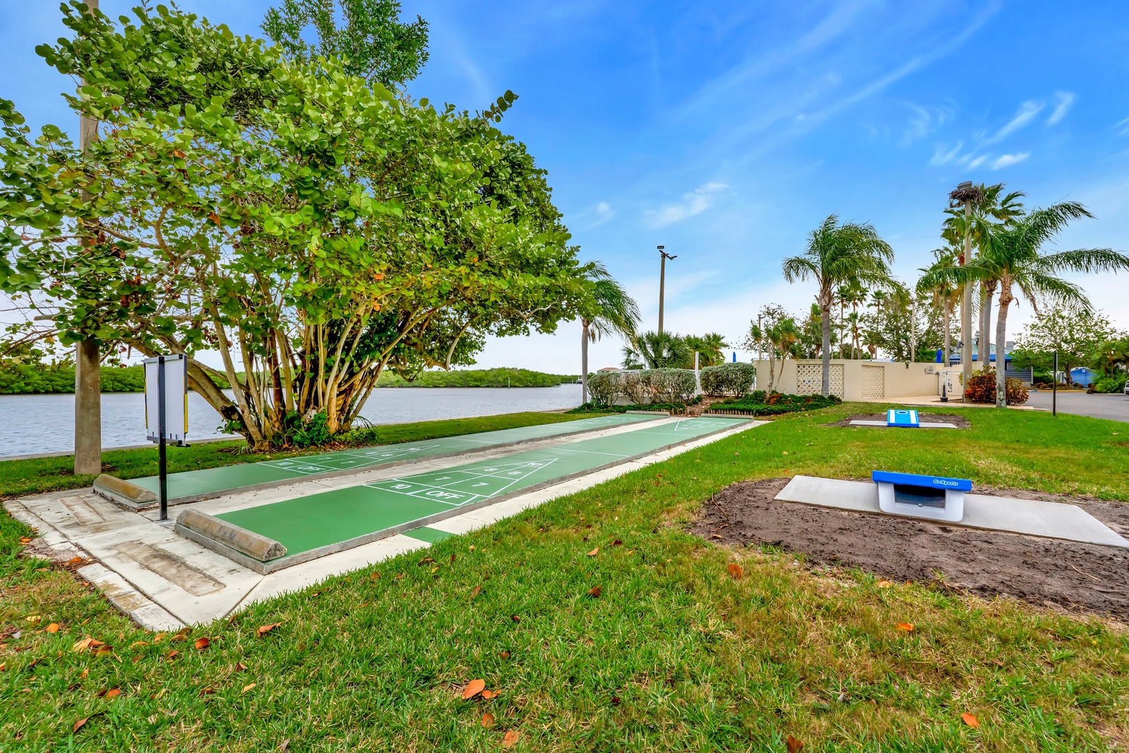 Scenic waterfront setting with shuffleboard court and lush tropical landscaping, perfect for outdoor recreation and enjoying Florida sunshine.