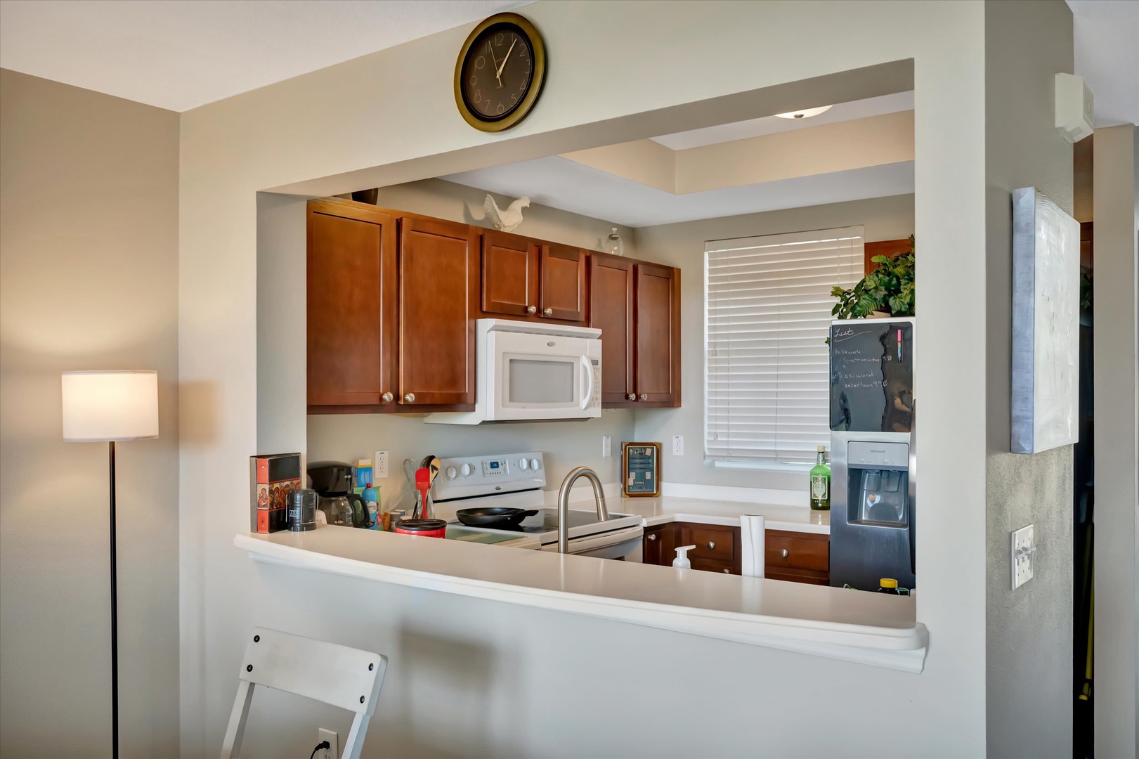 Your fully equipped kitchen features warm cherry cabinets, modern appliances including a microwave and stove, and a bright open layout perfect for preparing meals during your stay.