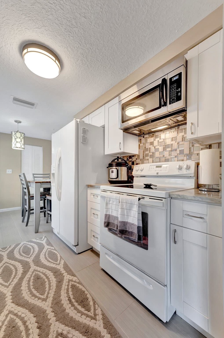 Step into your fully equipped kitchen where cooking feels effortless. Bright white cabinetry, modern appliances, and stylish mosaic backsplash come together in a welcoming space where you'll love preparing meals during your stay.