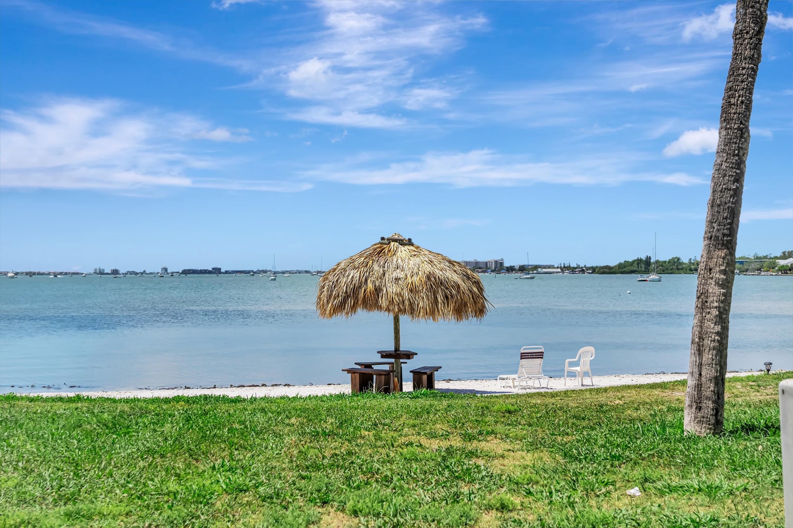 The property offers waterfront access with a private tiki hut and seating area overlooking calm bay waters, perfect for enjoying sunny days and coastal breezes.