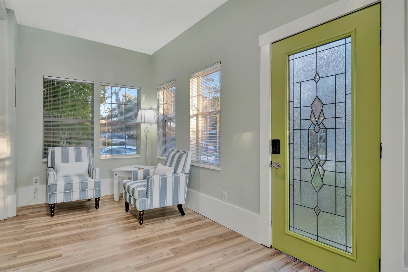 Step into your welcoming entryway, where natural light streams through large windows and a cheerful green door with elegant stained glass sets a warm, inviting tone for your stay.