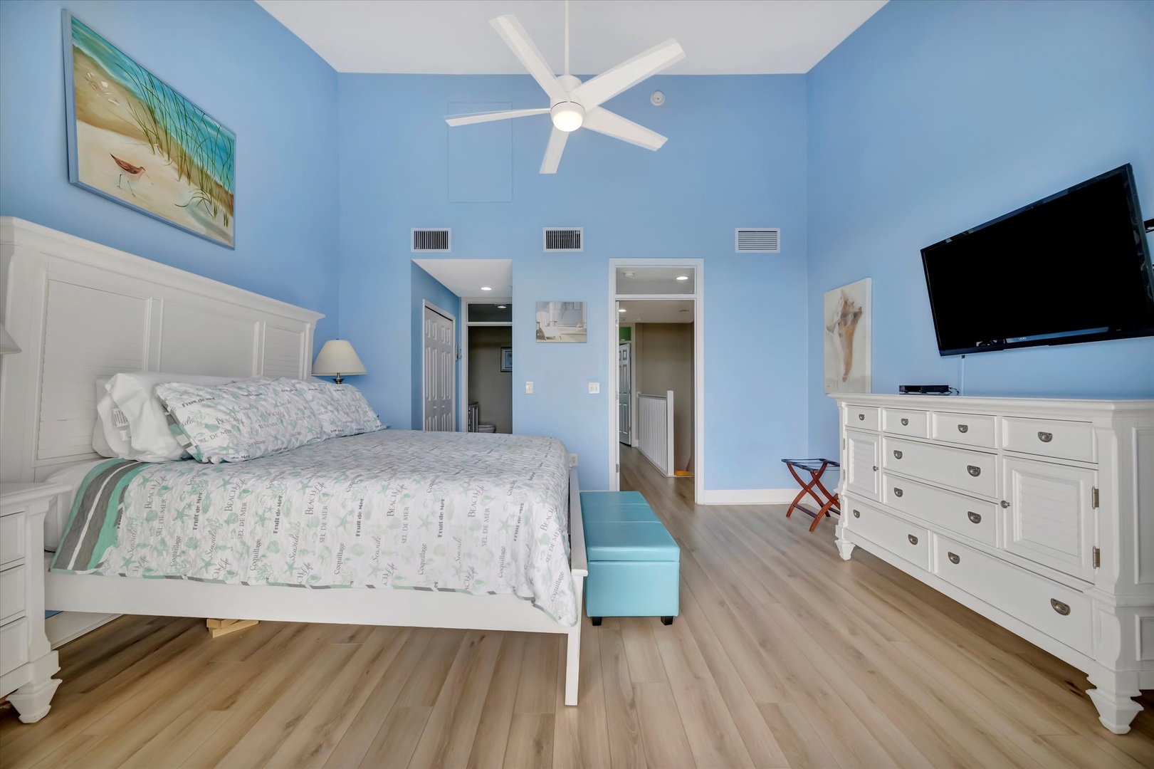 Sink into your peaceful coastal retreat with soothing blue walls, a plush bed, and breezy ceiling fan overhead. The room's airy design and beach-inspired touches invite you to unwind completely.