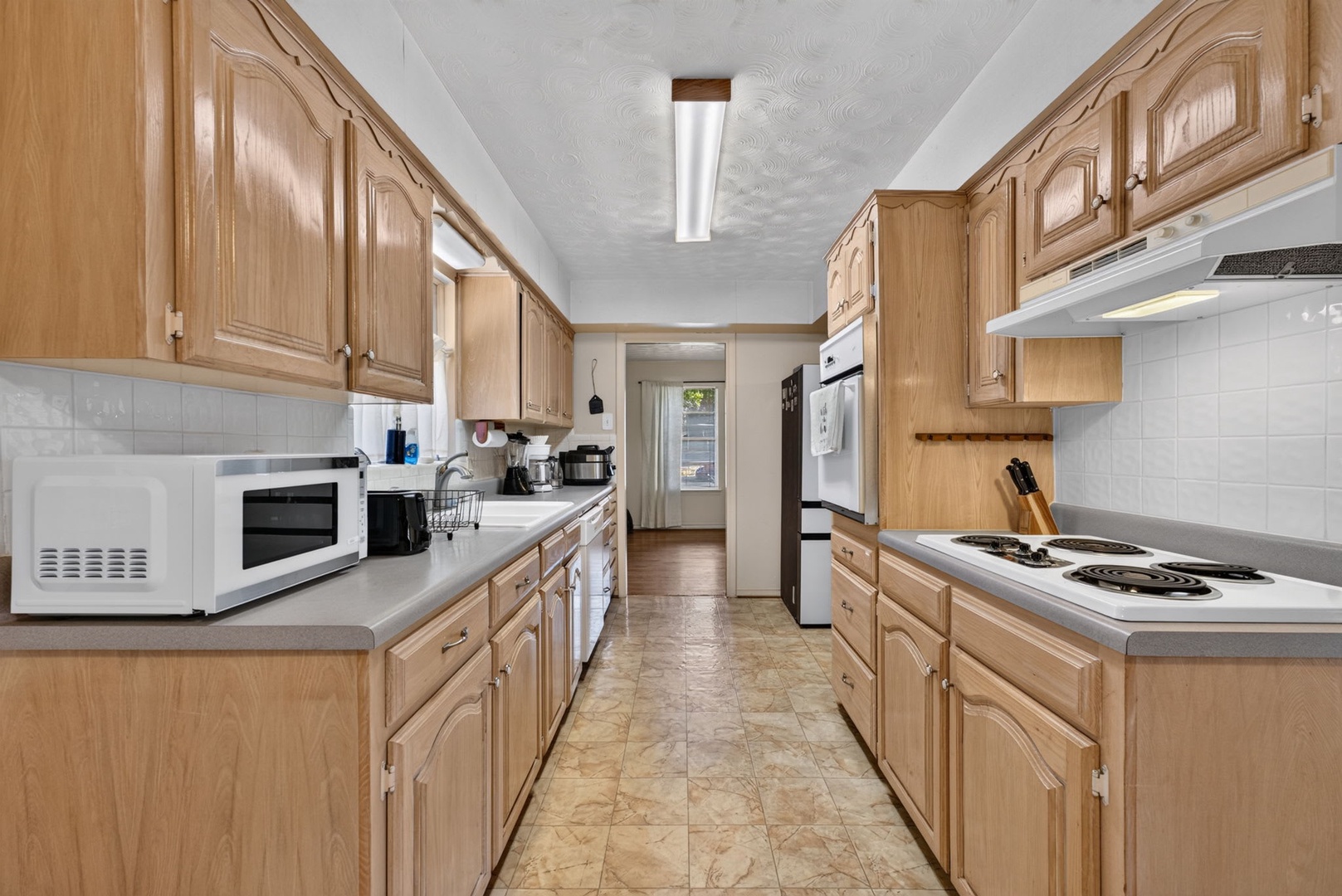 A spacious galley kitchen awaits you with warm wood cabinetry, full-sized appliances, and plenty of counter space to prepare your favorite meals during your stay.