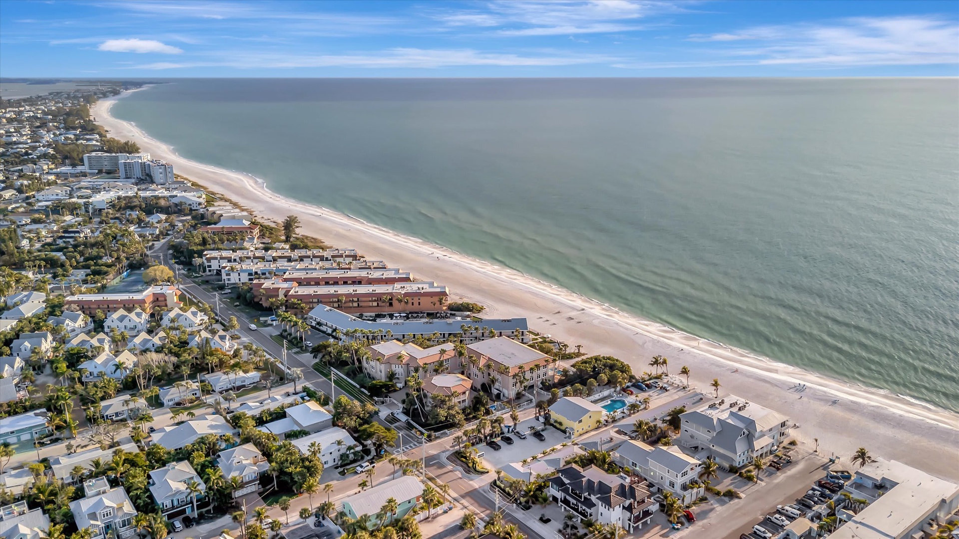 Aerial view capturing the beachfront property location along the Gulf Coast, with pristine white sand beaches and nearby residential neighborhood. An ideal setting for a coastal vacation rental.