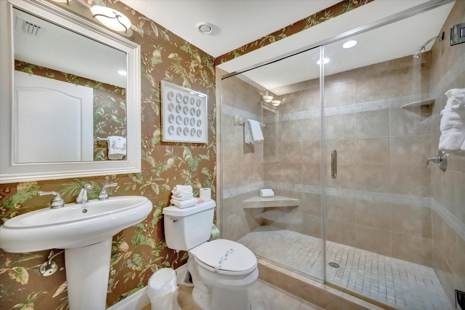 Refresh in your elegant bathroom featuring a spacious walk-in shower with rain showerhead, plush towels, and charming botanical wallpaper that adds a touch of vintage charm.