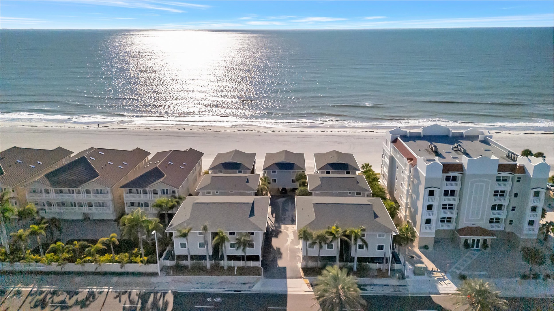Aerial view showcasing beachfront vacation rental properties along a pristine sandy coastline. The shimmering ocean and well-maintained residences offer an ideal coastal retreat.