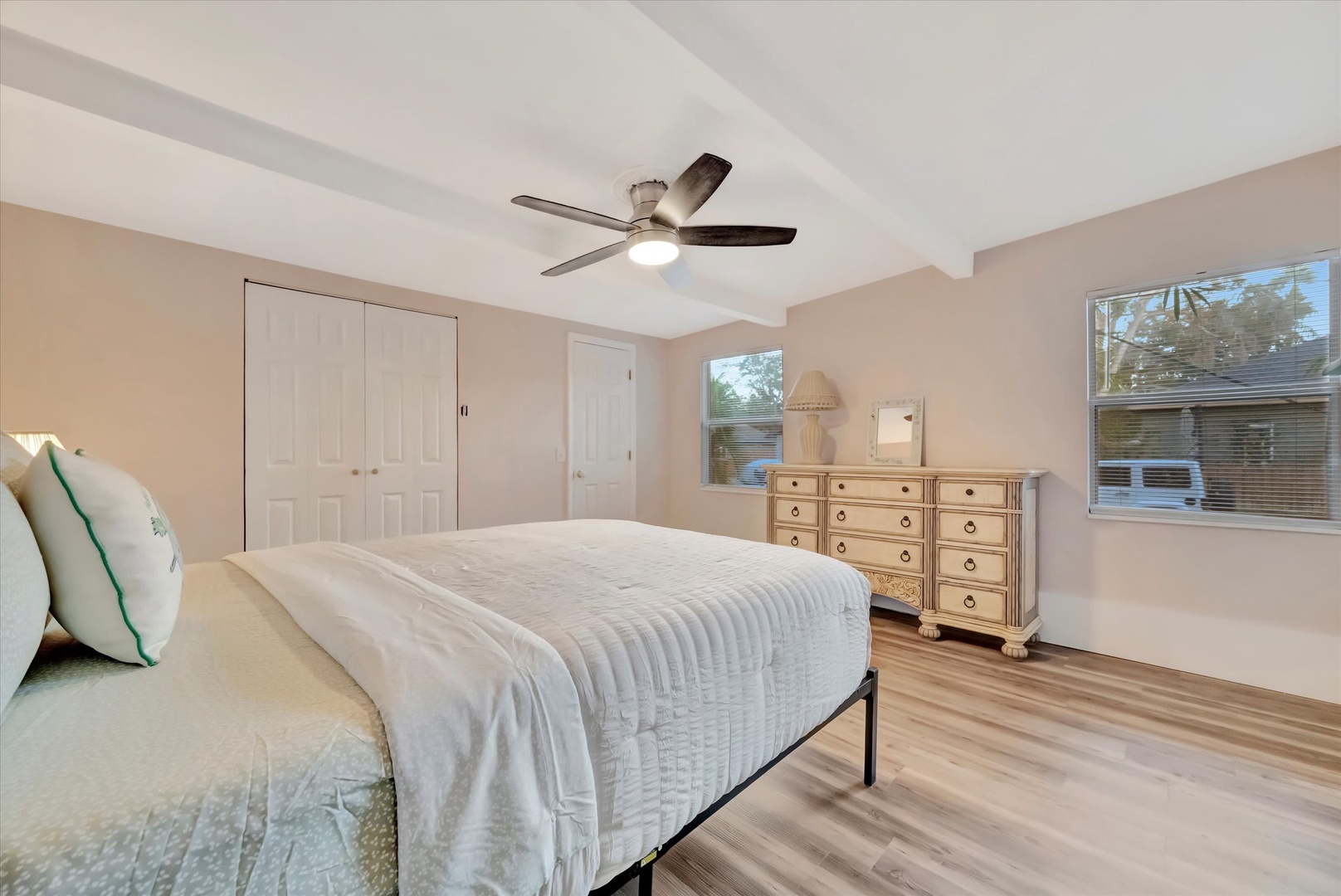 Unwind in your serene bedroom with crisp linens, warm wood floors, and a gentle ceiling fan to keep you comfortable. Natural light streams through large windows, creating a peaceful retreat for restful nights.