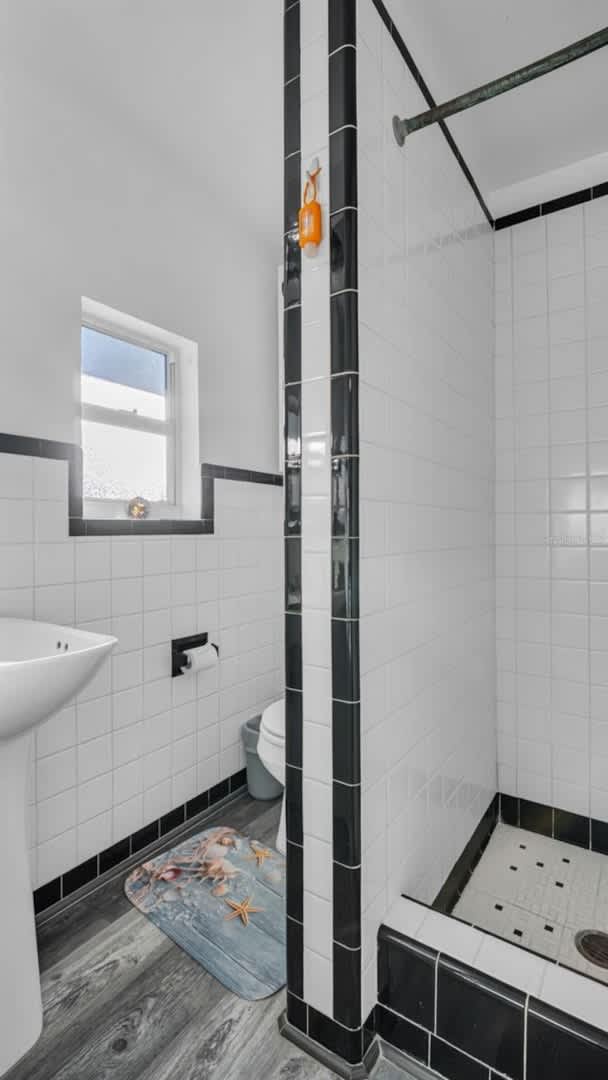 Your private bathroom features crisp white subway tiles with bold black accents, a spacious walk-in shower, and plenty of natural light from the window—a fresh, modern retreat perfect for unwinding after a day of adventure.
