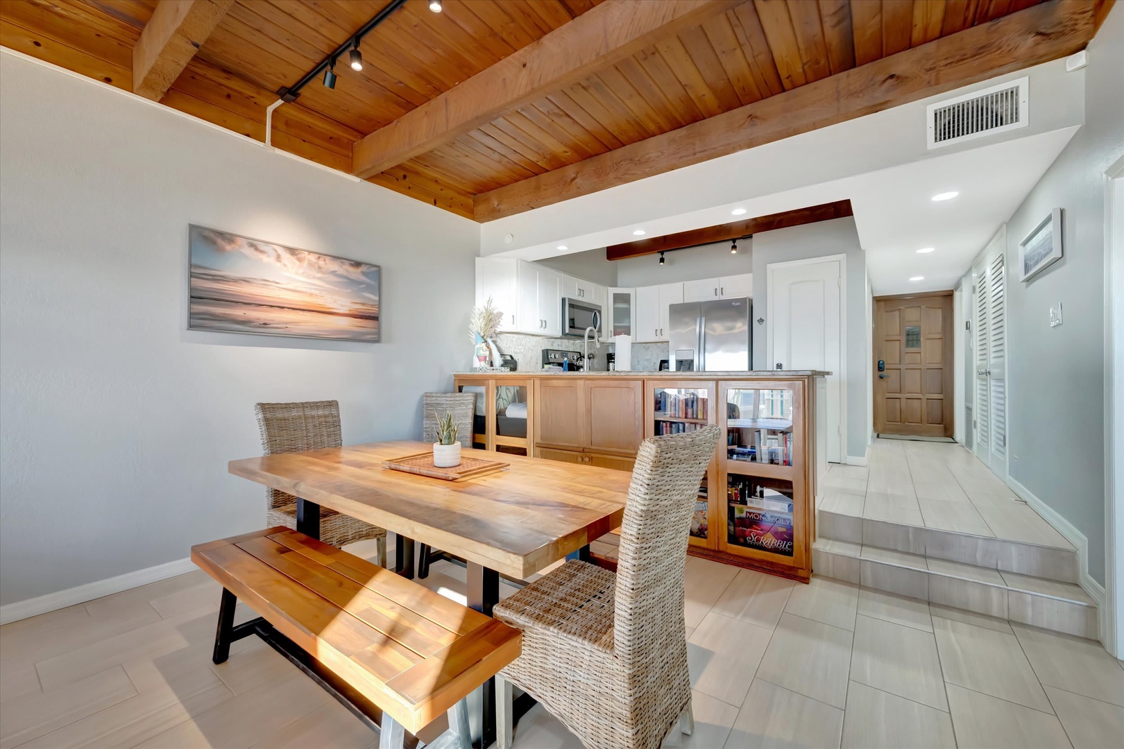 Gather around this inviting dining space where a warm wood table and vaulted cedar ceiling create an airy yet cozy atmosphere. Your fully equipped kitchen awaits just beyond, ready for meal prep and memorable conversations.