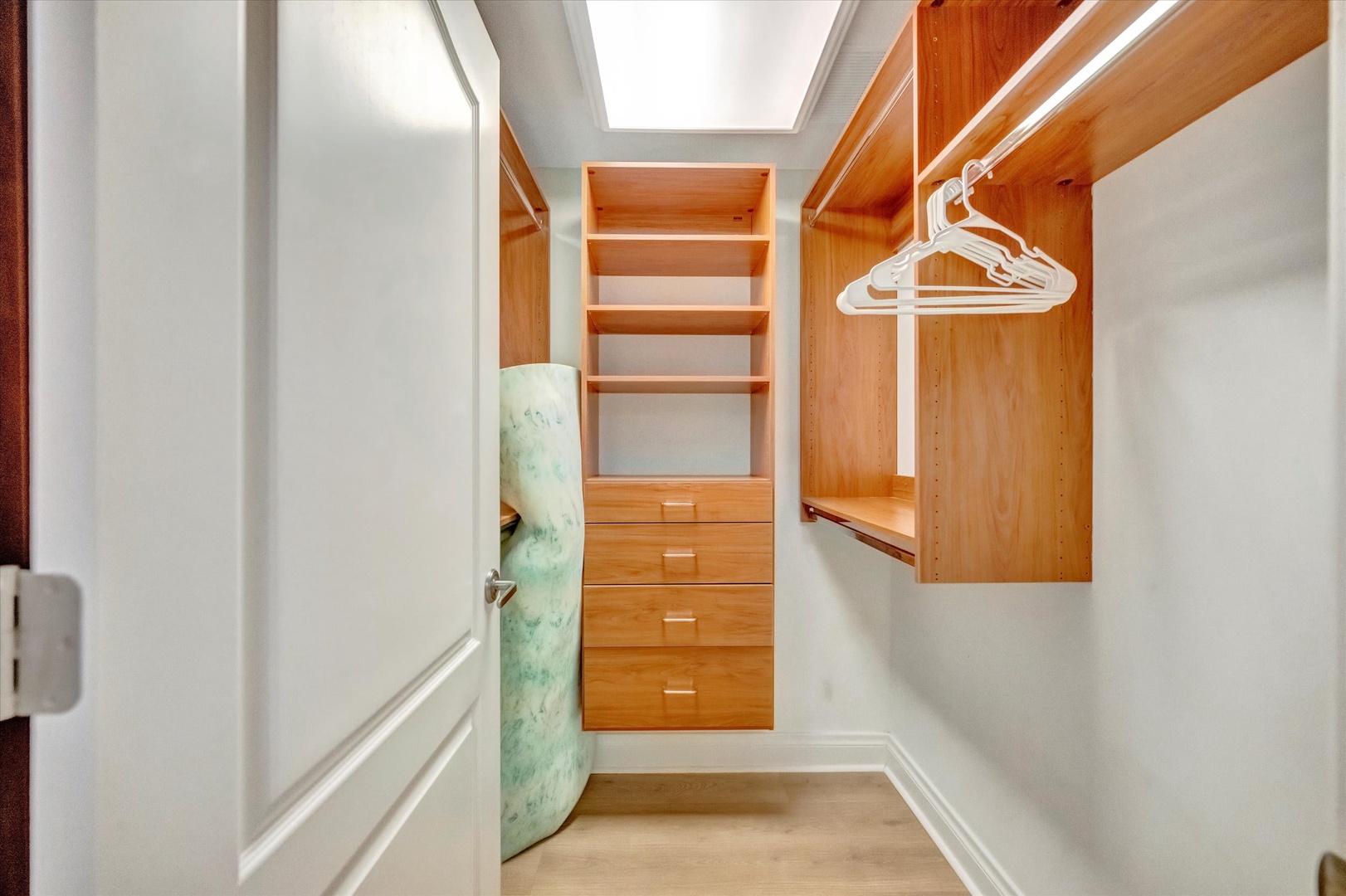 Your walk-in closet features beautiful wooden built-ins with shelving, drawers, and hanging rods—plenty of space to keep your wardrobe organized and accessible throughout your stay.