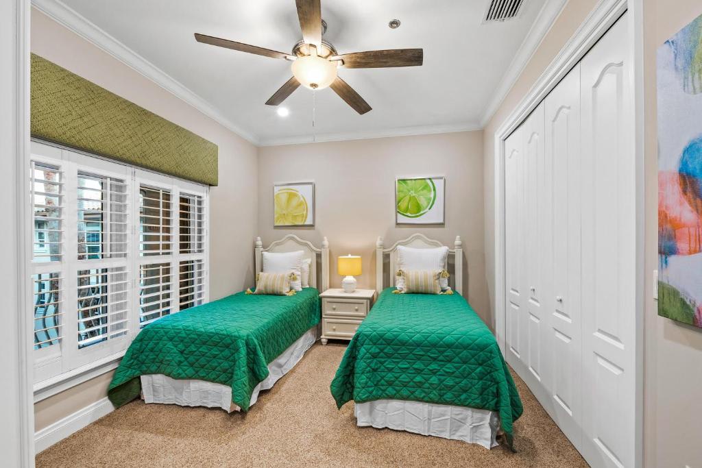 Your bright guest bedroom features twin beds dressed in cheerful emerald quilts, a ceiling fan to keep you comfortable, and playful citrus artwork that adds a fresh, tropical feel to your restful retreat.