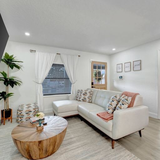 Unwind on the plush sectional in your cozy living space, where natural light fills the room and fresh greenery brings a calming, homey vibe to your stay.