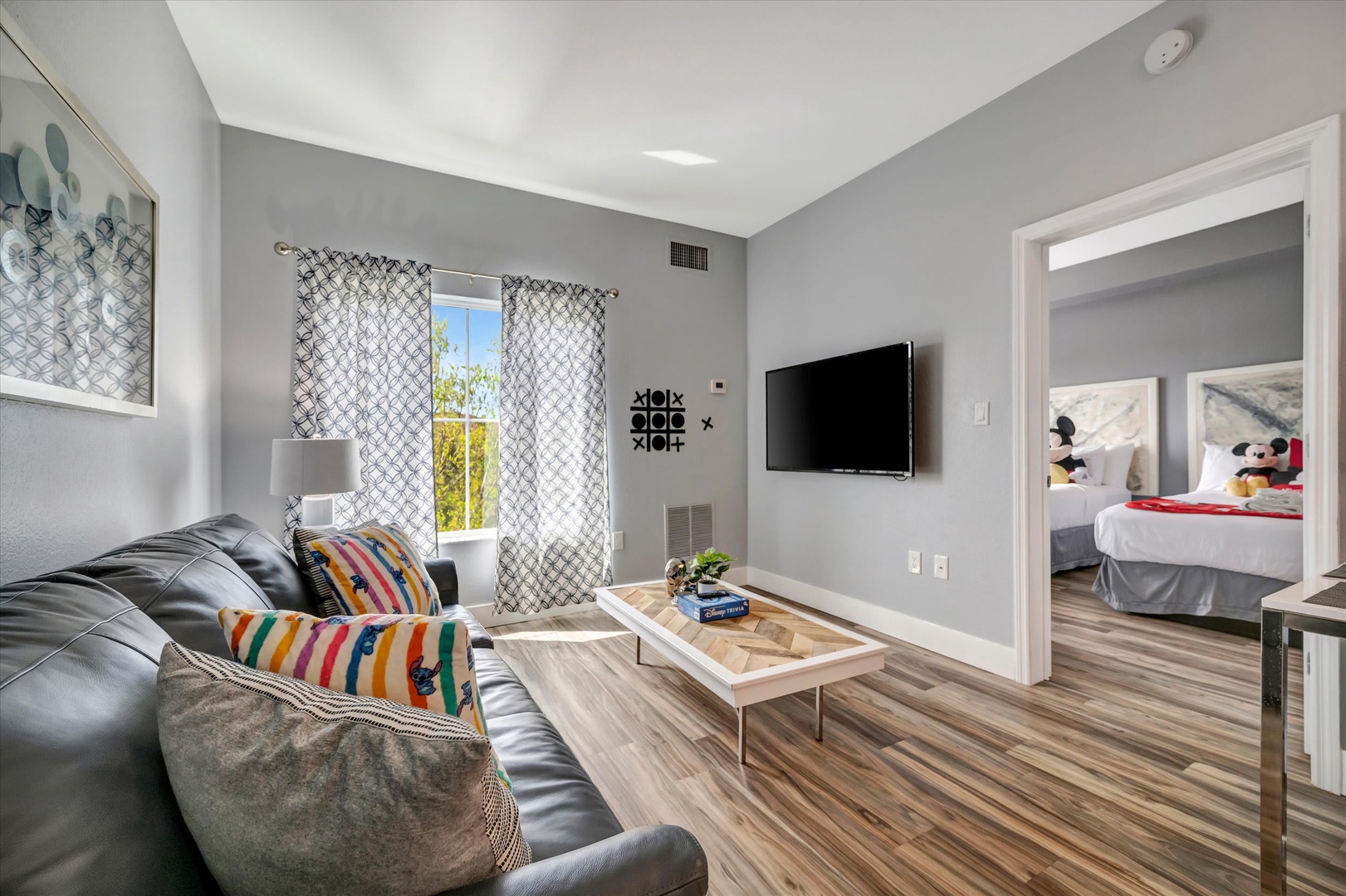 Bright, modern living space with natural light streaming through patterned curtains and a plush sofa—the perfect cozy retreat for your vacation getaway.