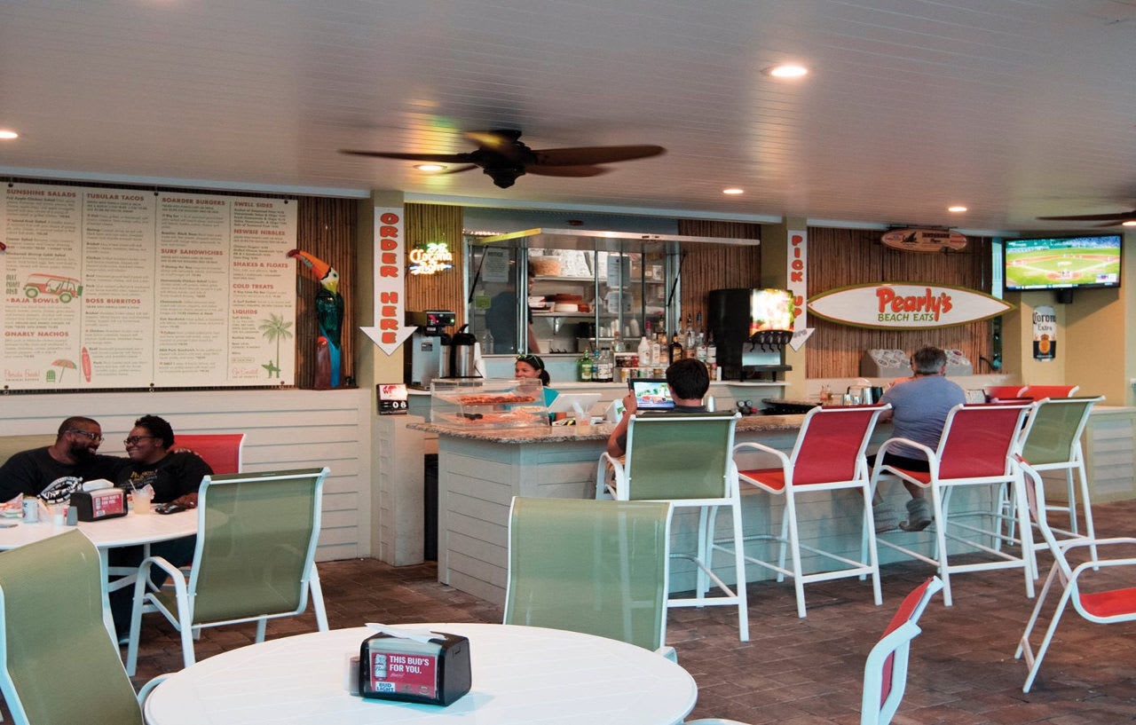 Pearl's Beach Eats offers a casual beachside dining atmosphere with colorful seating, a central bar area, and tropical-inspired decor—perfect for enjoying fresh coastal cuisine in a laid-back setting.