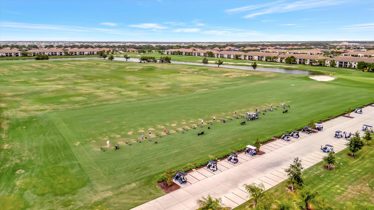 This aerial view showcases the property's prime location adjacent to championship golf greens, with residential buildings and water features dotting the expansive course landscape.