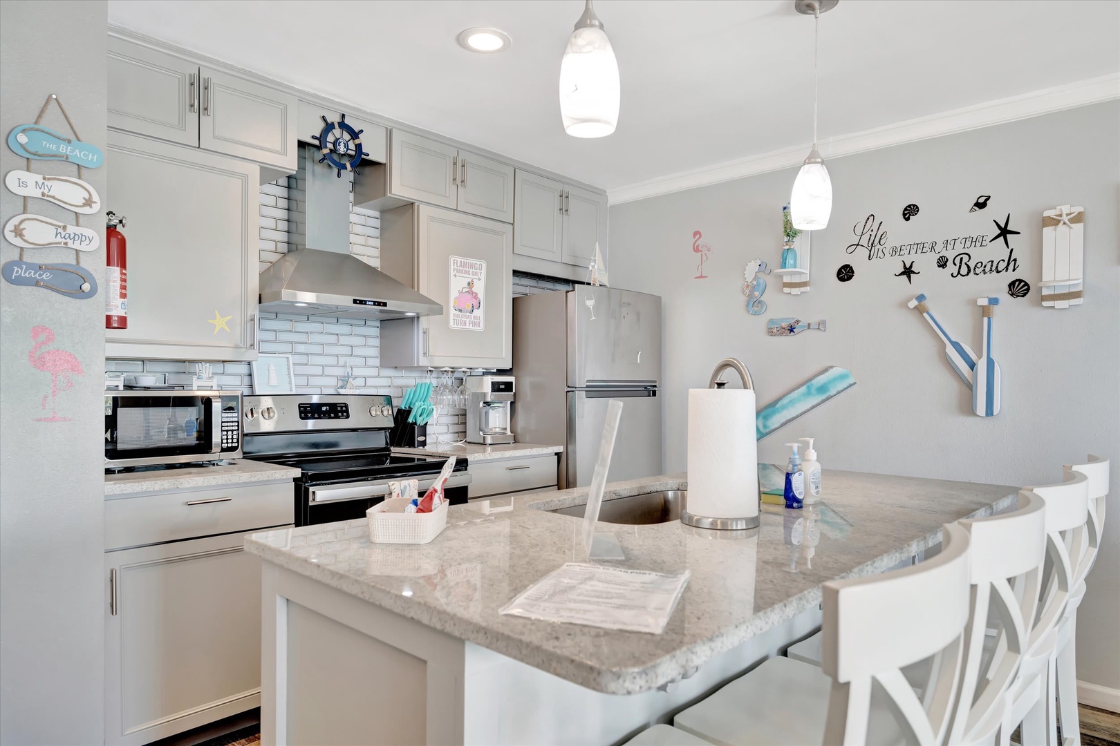 Step into your fully equipped kitchen featuring modern stainless steel appliances, bright white cabinetry, and a welcoming island with seating—perfect for gathering over morning coffee or whipping up a beachside feast.