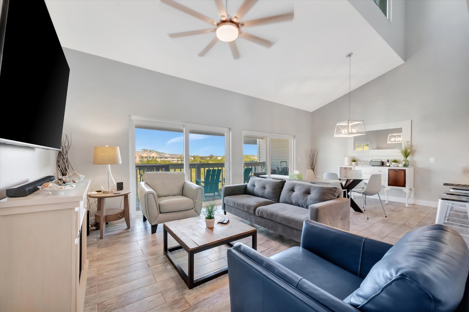Unwind in your bright, open living space where vaulted ceilings and a stylish ceiling fan create an airy, welcoming atmosphere. Through the windows, catch glimpses of desert hills framing the view beyond your private balcony.
