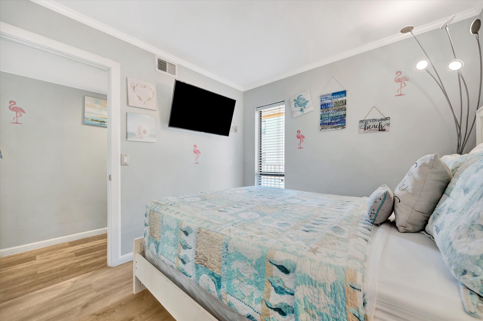 Drift off in your serene coastal retreat with soft hues, playful flamingo touches, and a cozy bed that invites relaxation after a day of exploring.