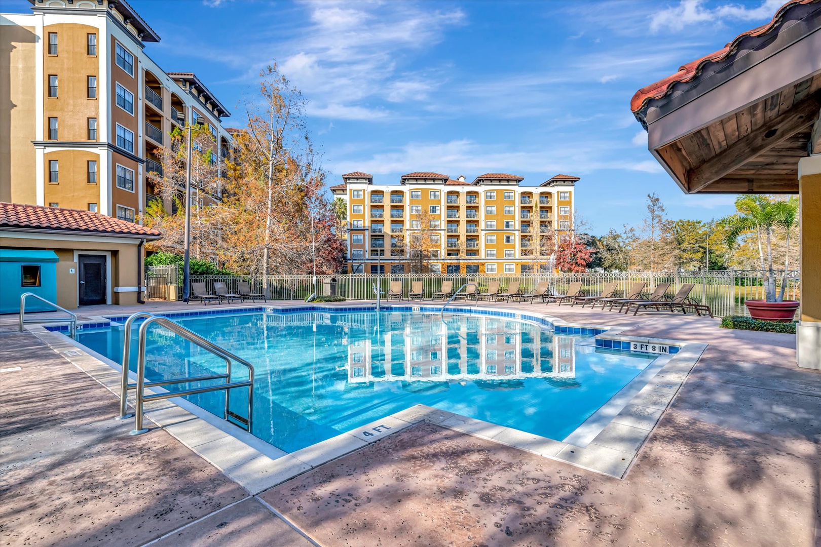 Sparkling pool area surrounded by lounge chairs and autumn trees, with the resort buildings providing a picturesque backdrop for sunny days and refreshing swims.
