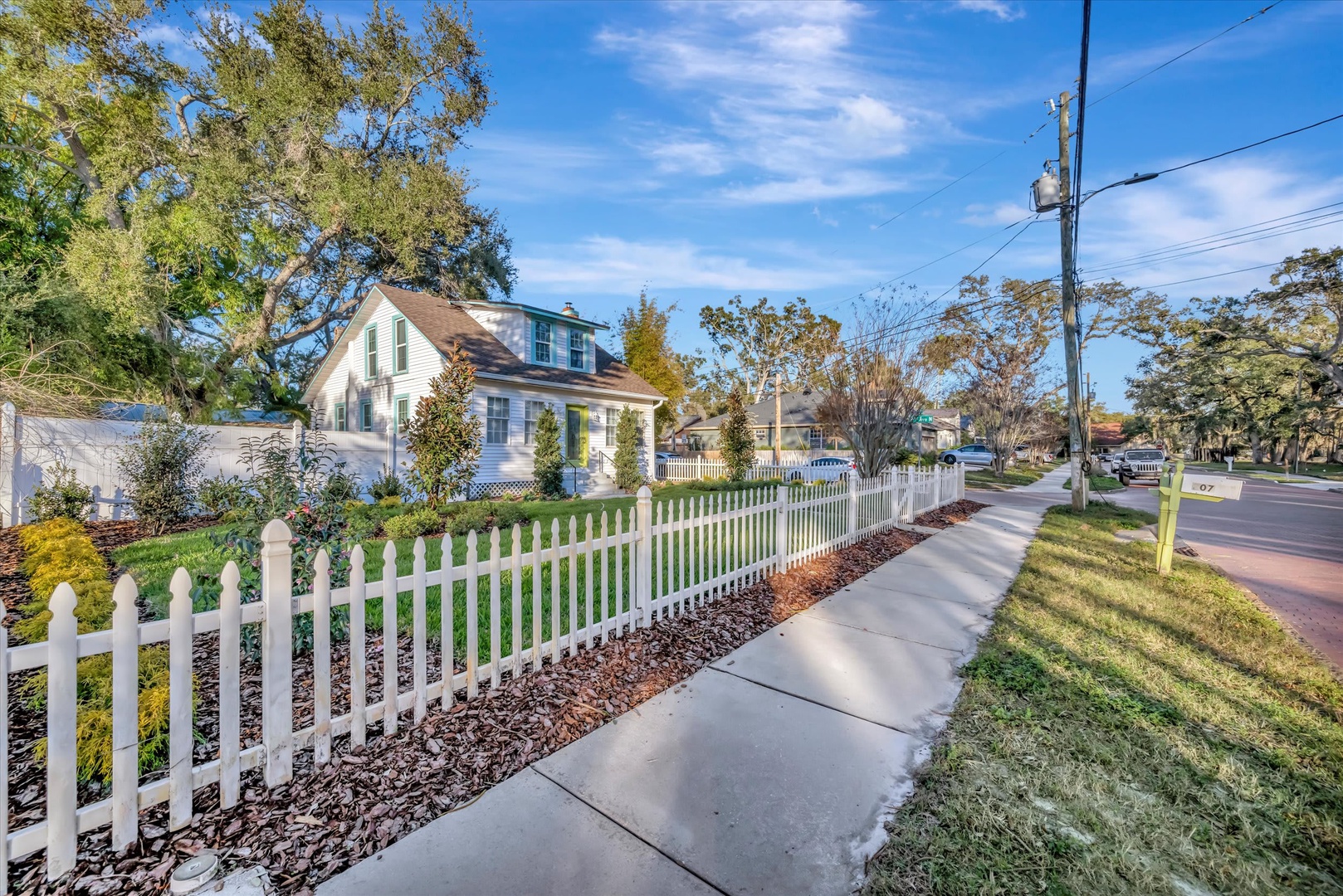 Charming white-picket-fenced property on a tree-lined residential street, offering a peaceful neighborhood setting with convenient sidewalk access.