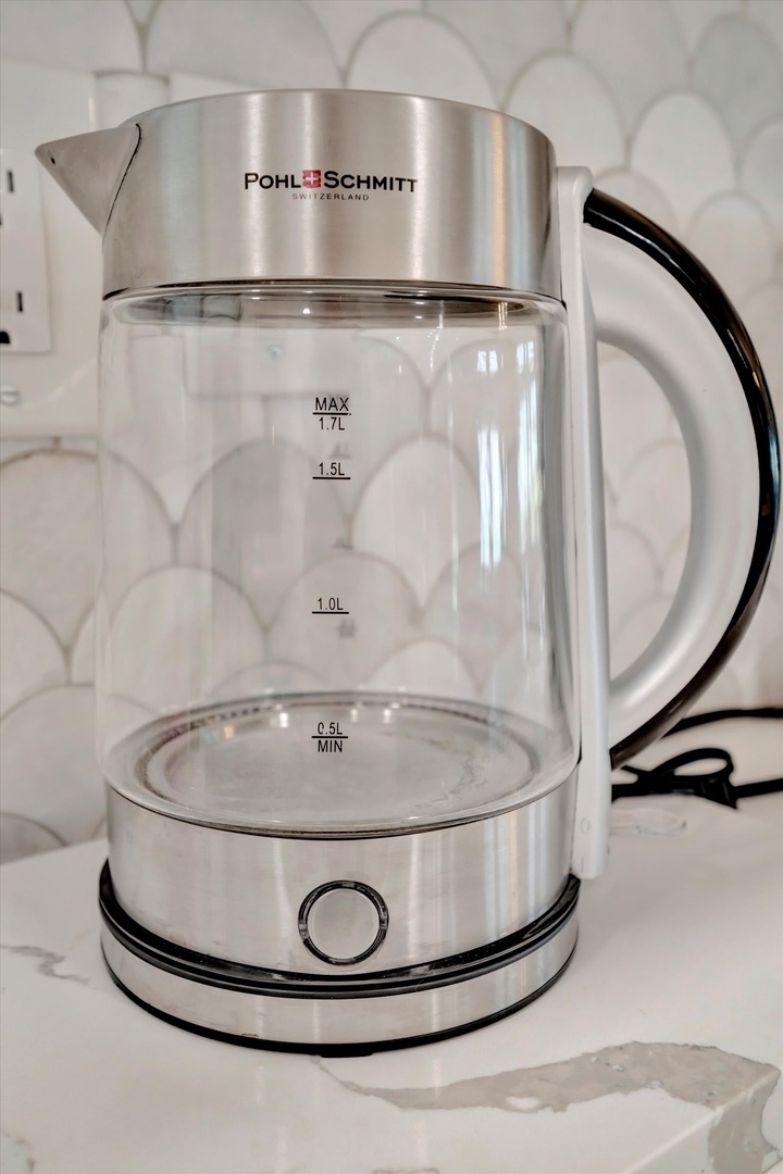 A sleek glass electric kettle sits ready on the counter to brew your morning tea or coffee—one of those simple touches that makes mornings feel effortless.