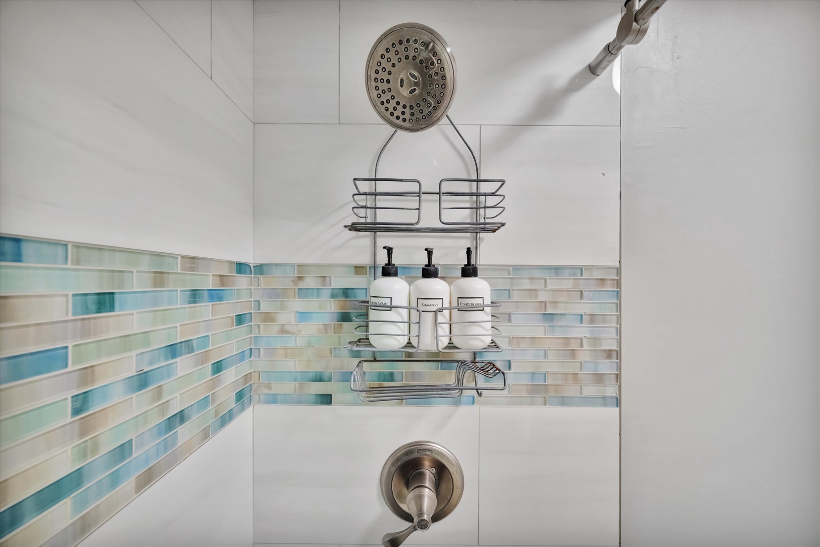 Refresh and unwind in your private shower, featuring a coastal-inspired tile design and thoughtful amenities for your stay.